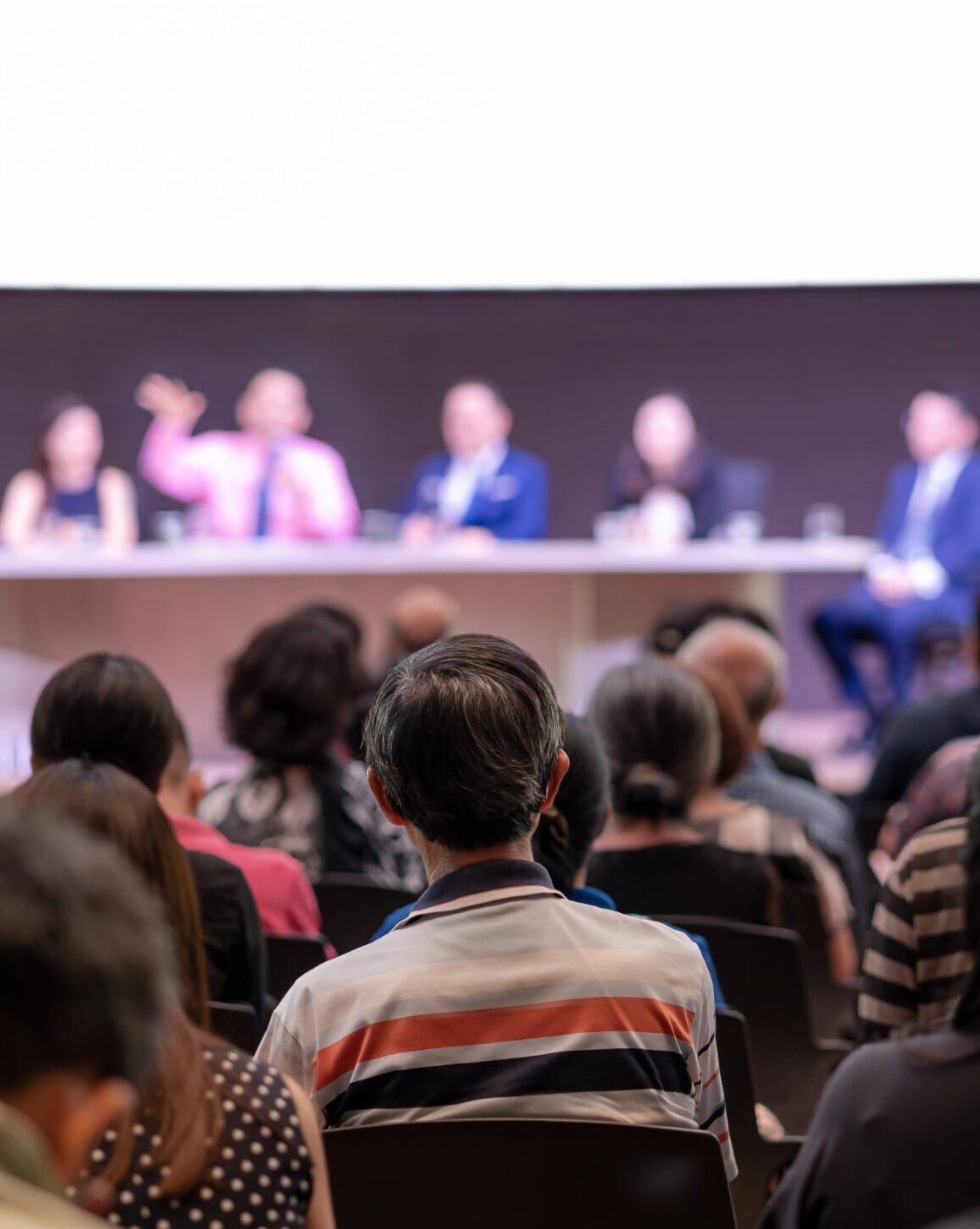 Rear view of Audience in the conference hall or seminar meeting which have Speakers are Brainstorming and talking on the stage, business and education about investment concept