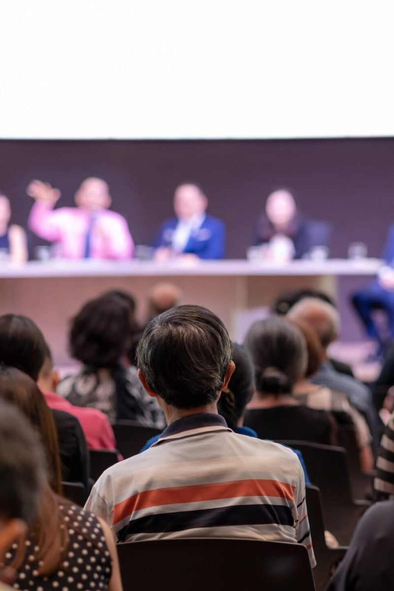 Rear view of Audience in the conference hall or seminar meeting which have Speakers are Brainstorming and talking on the stage, business and education about investment concept